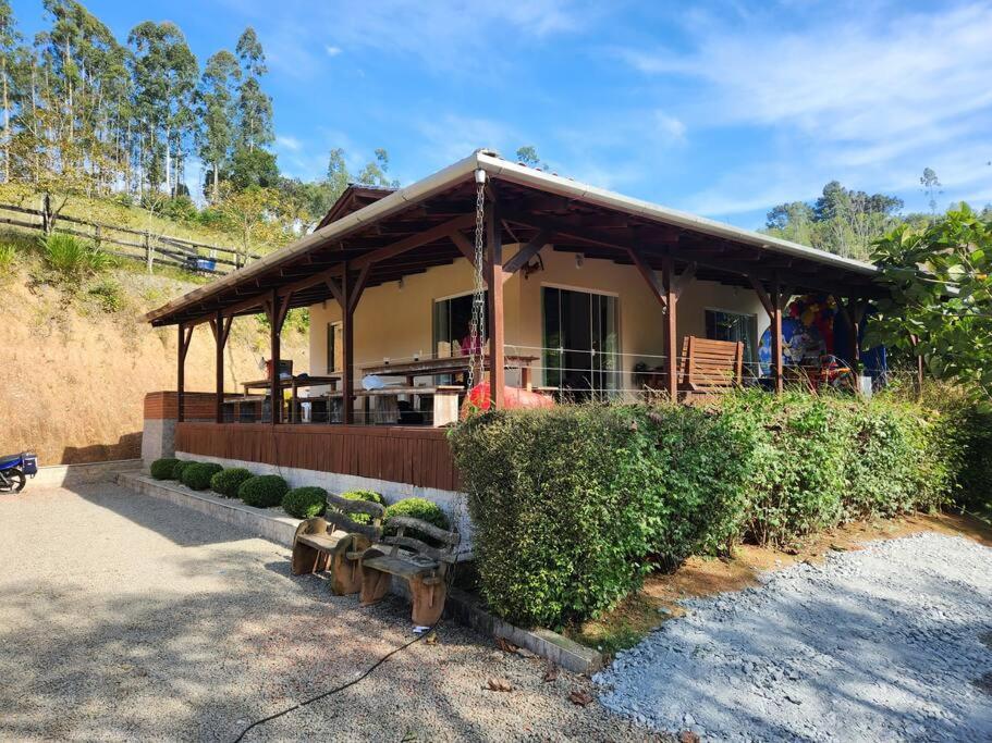 a house with a porch and benches in front of it at Casa do Campo in Rio do Sul