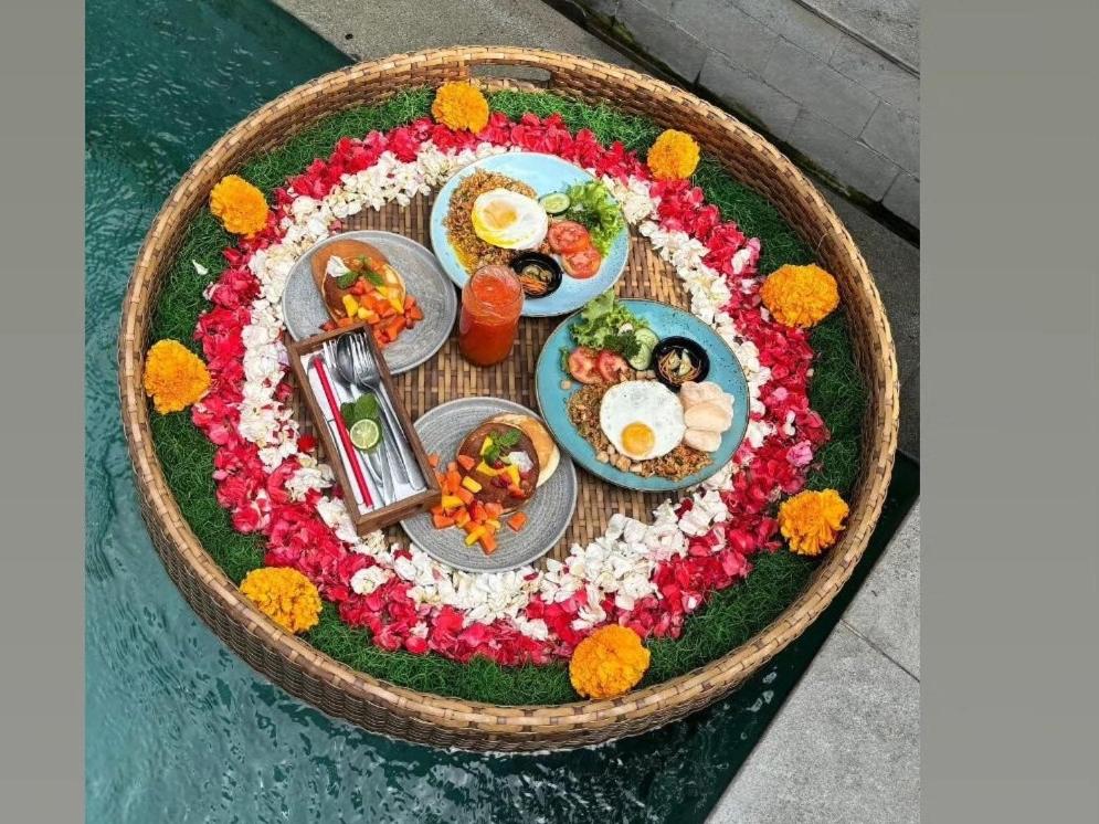 a breakfast table with food and flowers in a basket at Ubud Season Villas in Ubud