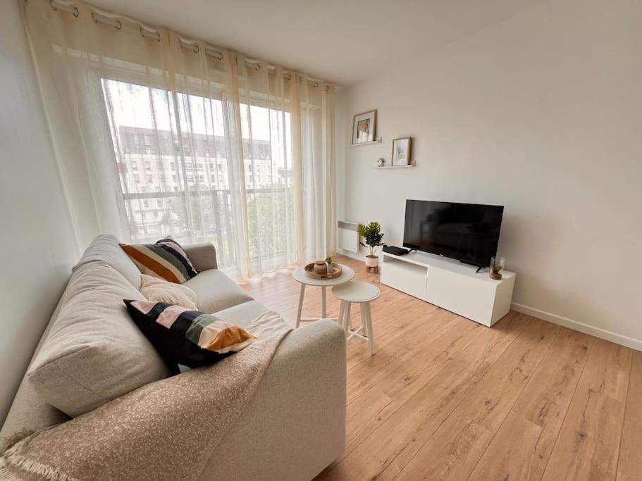 un salon avec un canapé et une télévision dans l'établissement T2 Paris - Stade de France Parking Gratuit, RER, à La Plaine-Saint-Denis