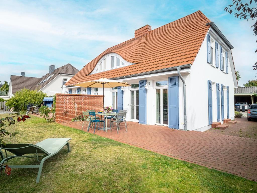 ein weißes Haus mit einem Tisch und einem Regenschirm in der Unterkunft Haus SEEGARTEN in Wustrow