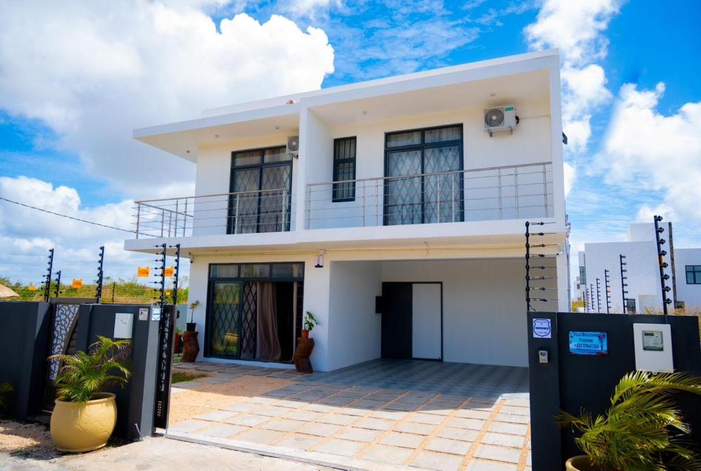 a white house with two parking meters in front of it at Villa Boulevard Paradise in Grand Baie