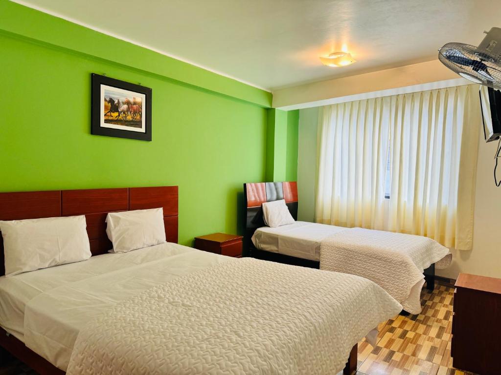 Zimmer mit 2 Betten und einer grünen Wand in der Unterkunft Hotel Puerto Bayovar II in Mala