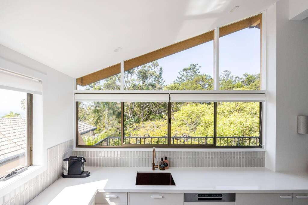 una cocina con una gran ventana sobre un fregadero en Otto Descola - Views, walk to Hastings St & beach, en Noosa Heads