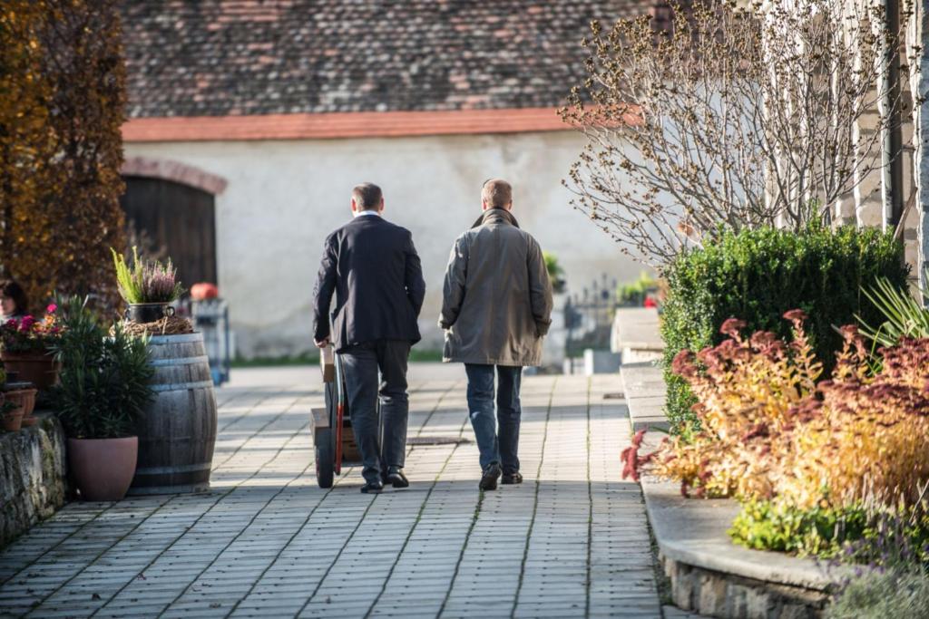 two men walking down a sidewalk with a suitcase at Remushof Jagschitz in Oslip