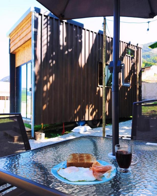 a table with a plate with a sandwich and a glass of wine at Tiny house Just Breathe in São Bento do Sapucaí