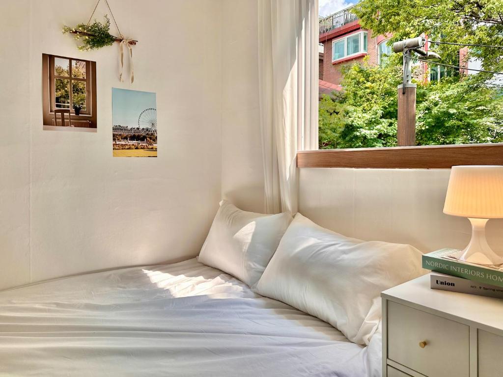 a white bed in a room with a window at GuRoom House Seoul in Seoul