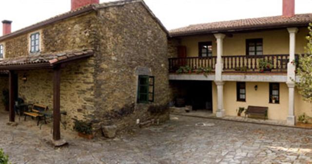 Edificio de piedra antiguo con balcón y patio en Casa Farruco, en Beigondo