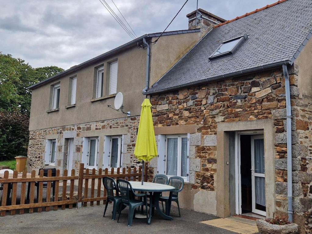 une table avec des chaises et un parapluie jaune devant un bâtiment dans l'établissement Cottage in France near Côte du Goëlo, à Plérin