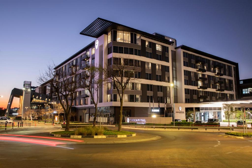 a large building on a street at night at The Capital Menlyn Maine in Pretoria