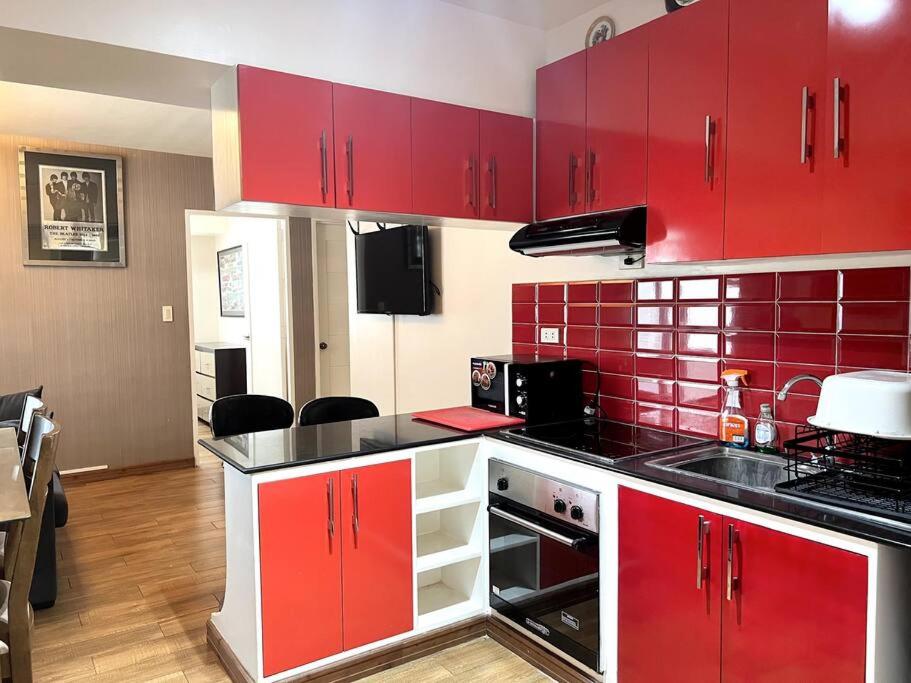 セブシティにある2-BR condo unit in IT Parkのキッチン(赤いキャビネット、黒いカウンタートップ付)