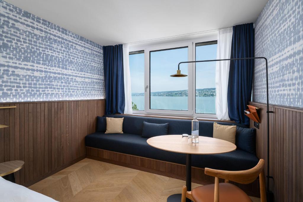 a room with a blue couch and a table and a window at The Yarn in Horgen