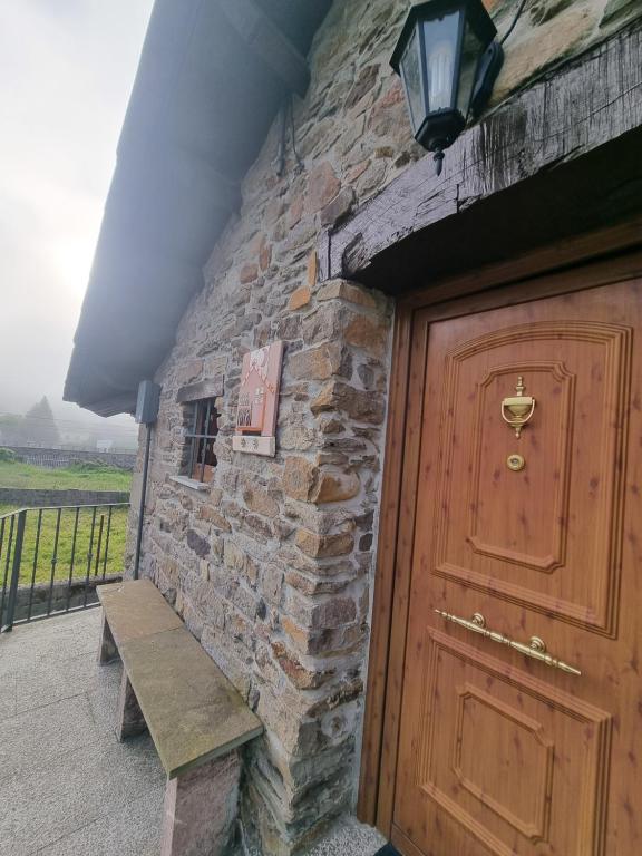 ein Steingebäude mit einer Holztür und einer Bank in der Unterkunft Casa Rural Maria de Isidro in Caboalles de Arriba