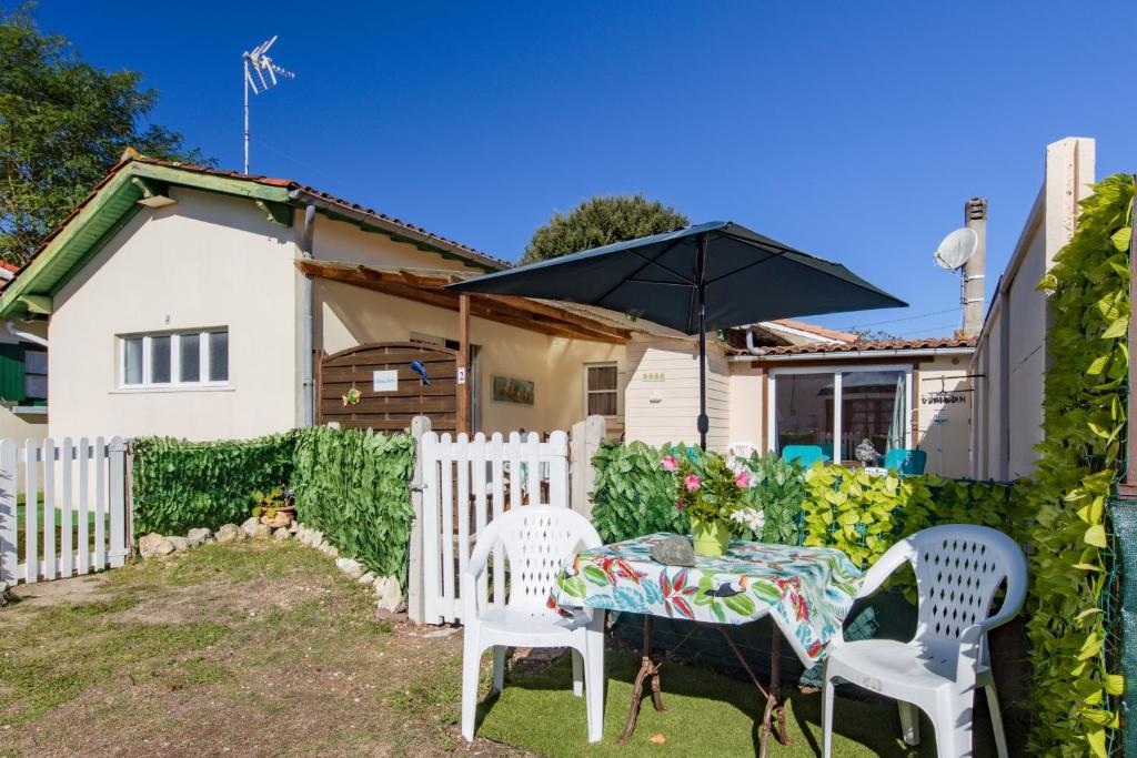 une arrière-cour avec une table, des chaises et un parasol dans l'établissement Villa Chouchou Côte Atlantique n2, à Soulac-sur-Mer