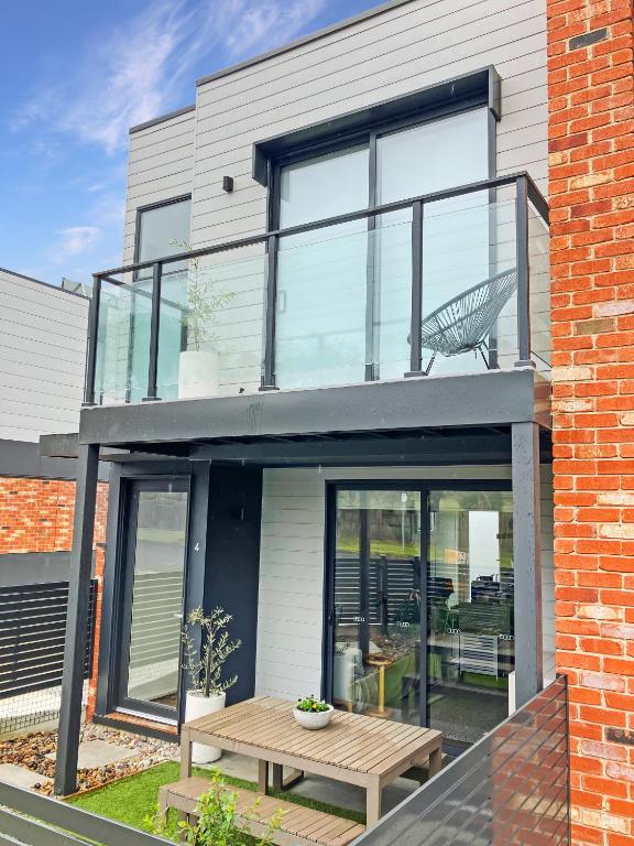 a house with large glass windows and a wooden table at Private Room & Ensuite, in hosted-shared Modern 2 bedroom Apartment - full use of all home facilities in Geelong