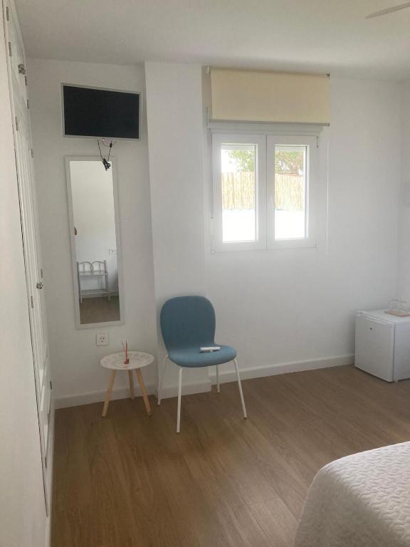 a bedroom with a blue chair and a mirror at Alojamiento Rural Al´Mare in Conil de la Frontera