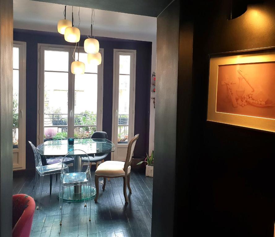 a dining room with a glass table and chairs at Bel appartement à Clichy sur Seine in Clichy