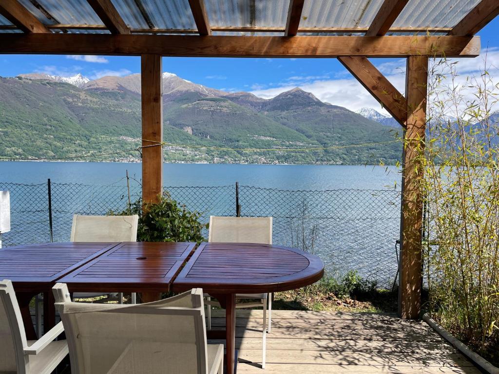 a wooden table and chairs with a view of a lake at Bungalow Lido Eve in Colico