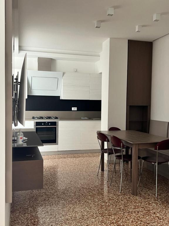 a kitchen with white cabinets and a table and chairs at Le Piazzette 2 in Schio