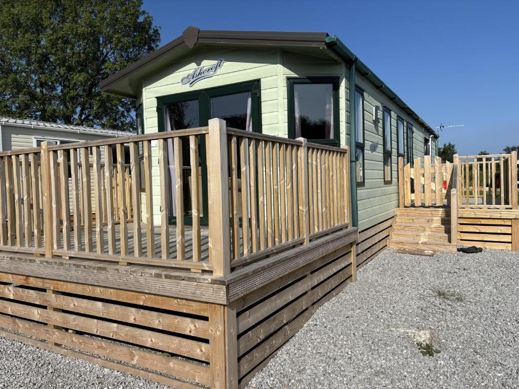a green tiny house with a wooden deck at Tranquil Lodge 2 Bed Sleeps 4 Free Parking in Preston