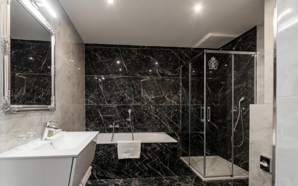 a black tiled bathroom with a sink and a shower at Grandhotel Brno in Brno