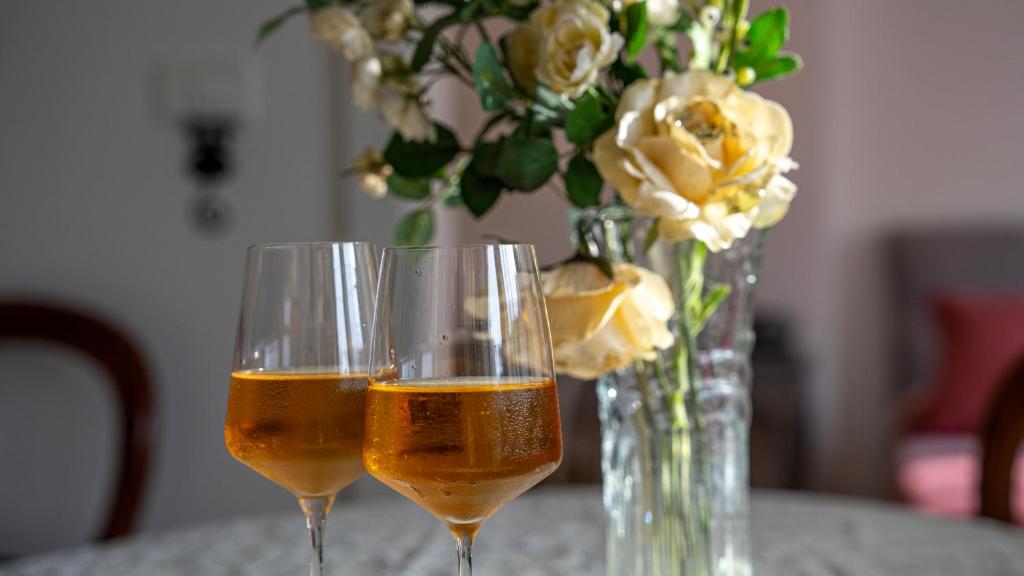 two glasses of wine next to a vase of flowers at apartman Frida in Zagreb
