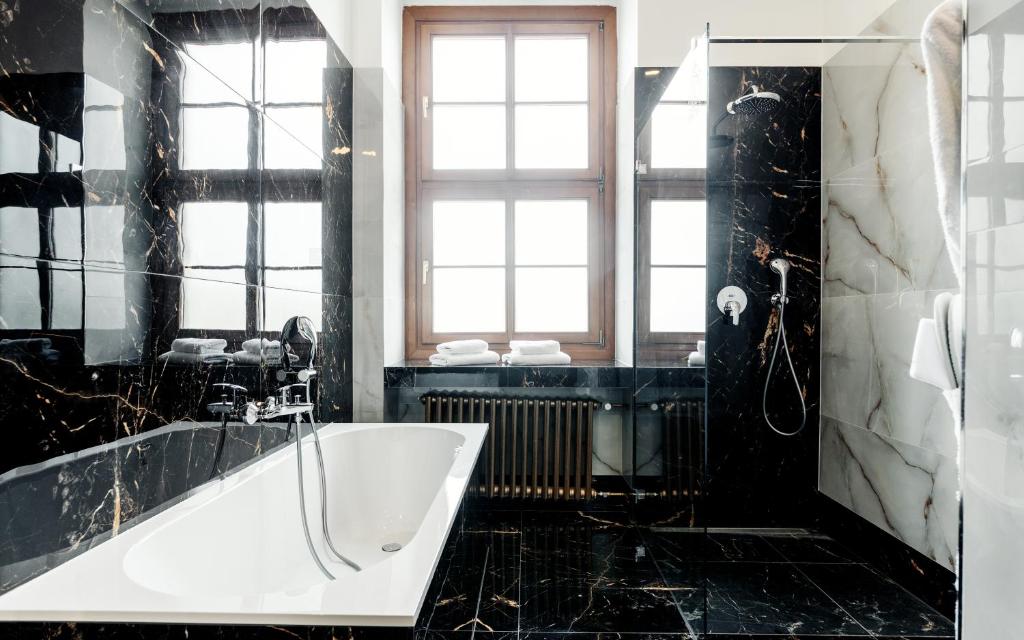 a black and white bathroom with a tub and a window at Grandhotel Brno in Brno