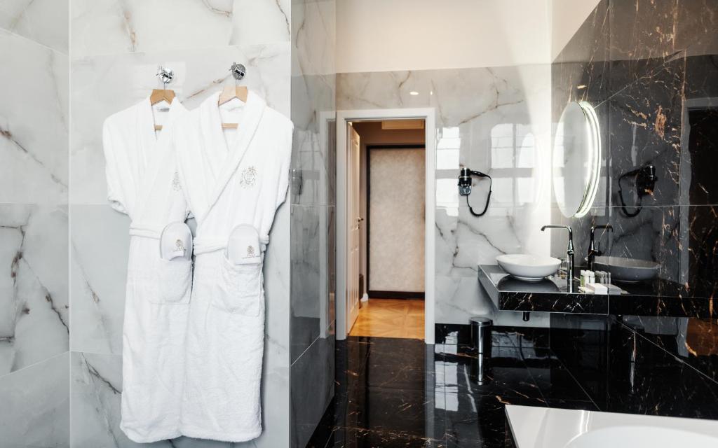 a bathroom with white robes hanging on a wall at Grandhotel Brno in Brno