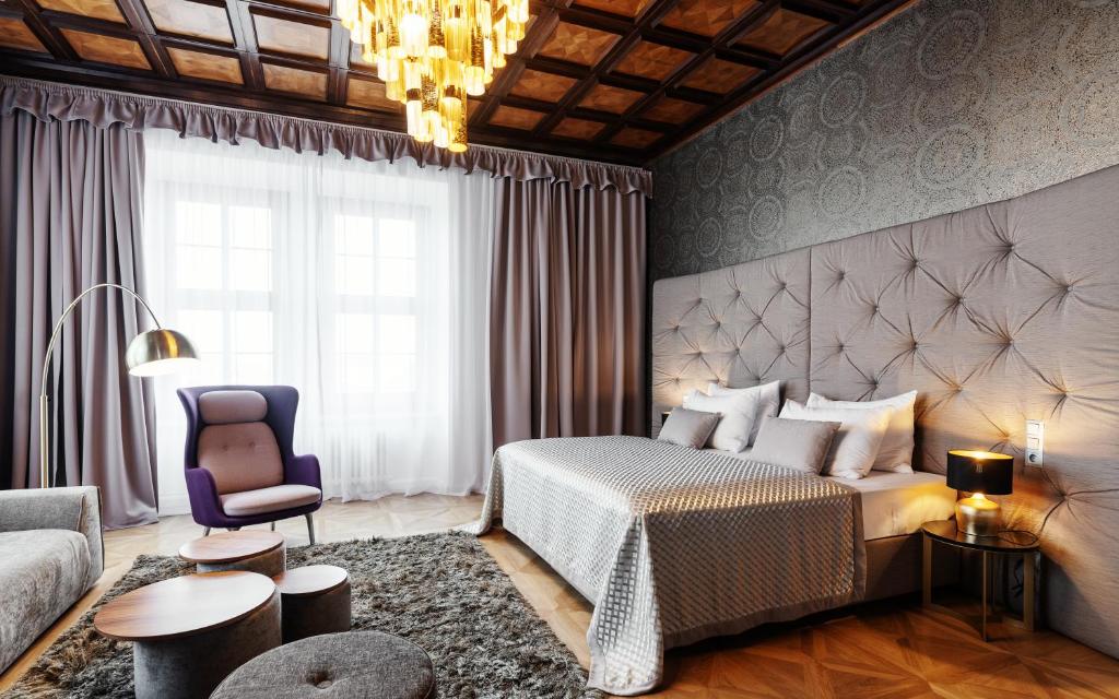 a bedroom with a bed and a couch and a chair at Grandhotel Brno in Brno