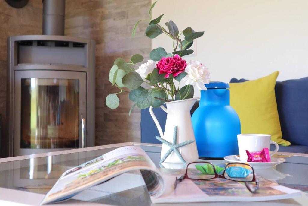a table with a book and a vase with flowers and glasses at Ferienhaus Zimmers-Nordseehaus in Dorum Neufeld