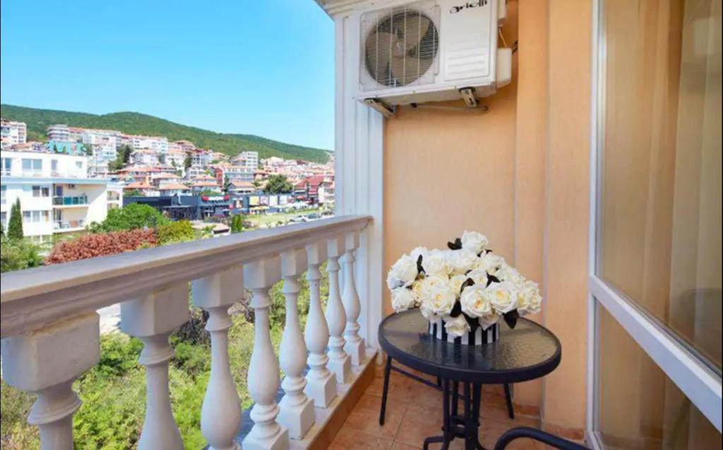 a table with flowers on top of a balcony at Уютно студио до морето - апартаменти 25 и 26, топ локация - Cozy Studio by the Sea - Apartments 25 and 26 Top Location in Sveti Vlas