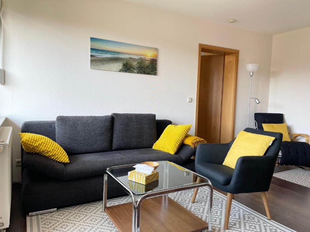 a living room with a black couch and yellow pillows at Ferienwohnung Laura in Bad Sachsa