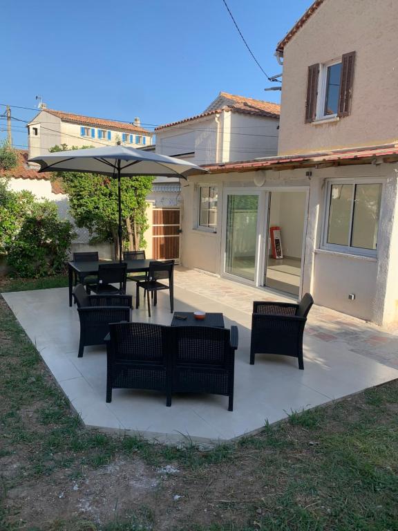 un patio avec tables, chaises et un parasol dans l'établissement Maison de pécheur, à Saint-Elme