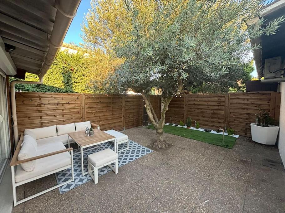 un patio con un sofá, una mesa y un árbol en Villa Centre Mandelieu-la-Napoule, en Mandelieu-la-Napoule