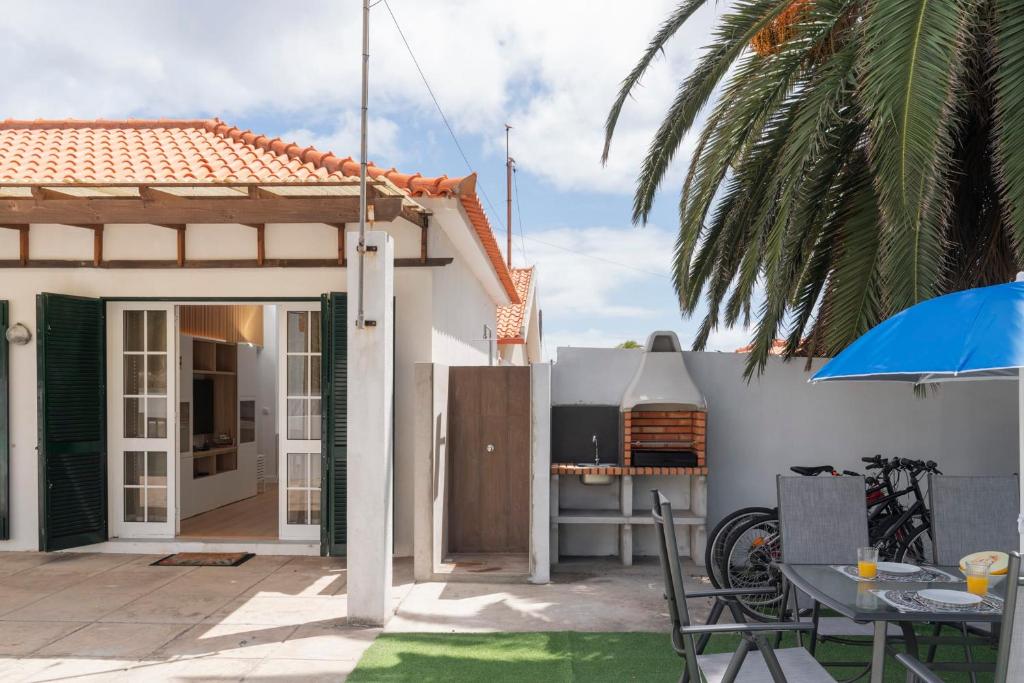 a patio with a table and a grill and a house at Casa da Palmeira by An Island Apart in Porto Santo
