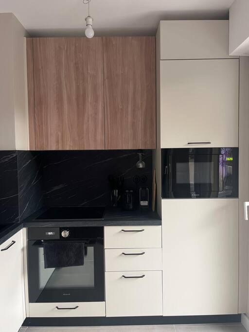 Il comprend une cuisine équipée d'une cuisinière noire et de placards blancs. dans l'établissement Studio neuf à 5 min plages et gare, à Vallauris