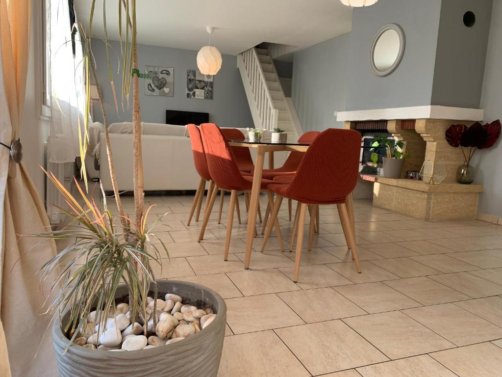 a living room with a table and red chairs at Maison aux portes de Chambord in Saint-Laurent-des-Eaux