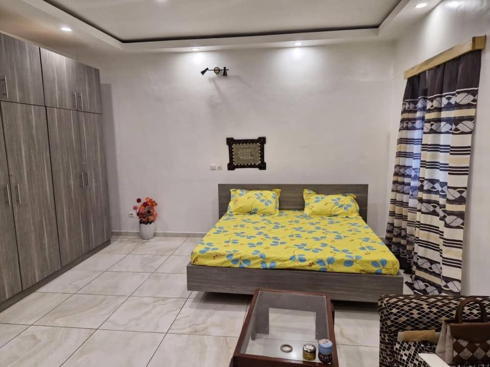 Cocody saint Jean في أبيدجان: غرفة نوم بسرير مع شراشف صفراء وطاولة