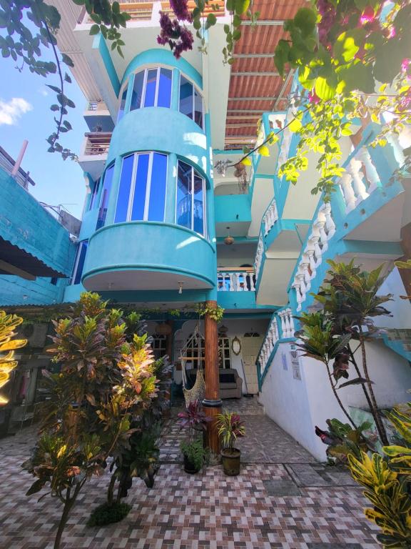 a large blue building with plants in front of it at Mandala’s Hostal in San Pedro La Laguna