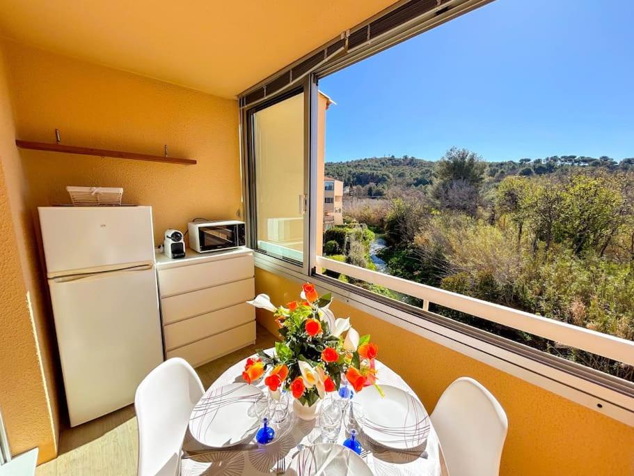 une salle à manger avec une table et une grande fenêtre dans l'établissement Coquet studio dans résidence avec piscine Sanary, à Les Playes