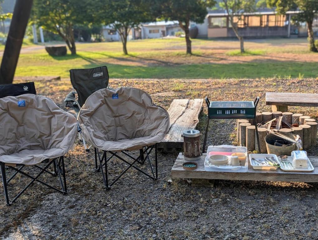 two chairs and a table in a park with a picnic table at Seiryukyou in Nishinoomote