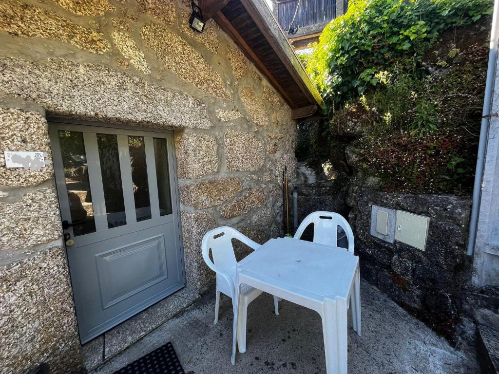 einen weißen Tisch und zwei Stühle vor einem Gebäude in der Unterkunft Natura Gerês in Valdosende