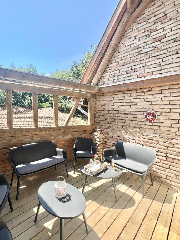 un patio avec des chaises et des tables sur une terrasse en bois dans l'établissement Townhouse in the countryside, à Berstett