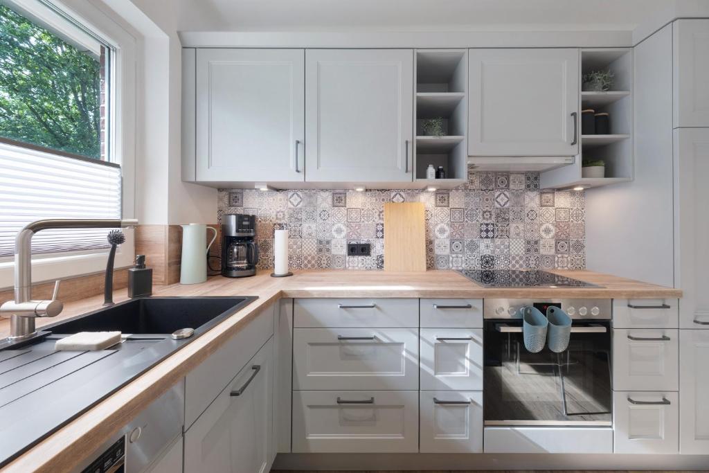 une cuisine avec des armoires blanches et un évier dans l'établissement Ferienhaus Anna Elbe, à Wischhafen