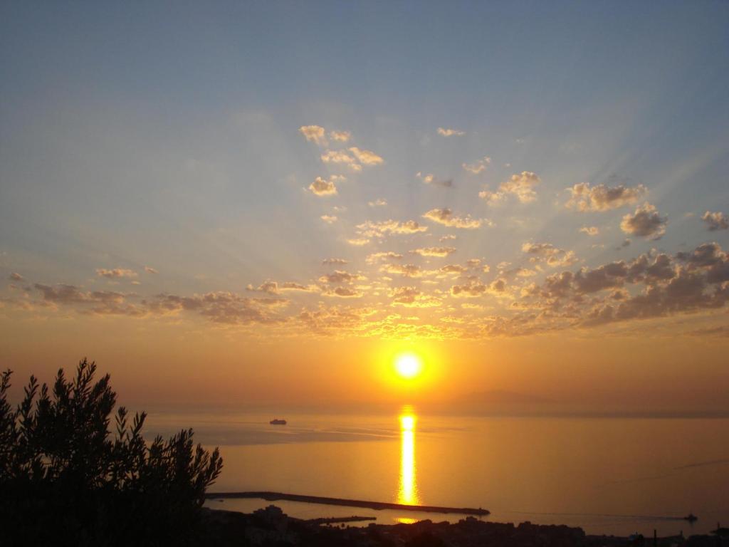 un coucher de soleil sur l'eau avec un bateau au loin dans l'établissement Ventilizia, à Bastia