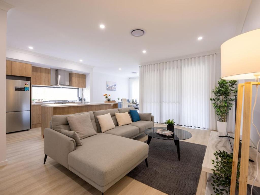 ein Wohnzimmer mit Couch und Küche in der Unterkunft Brand New 4Bs Home near Shops and Park at Greenbank in Greenbank