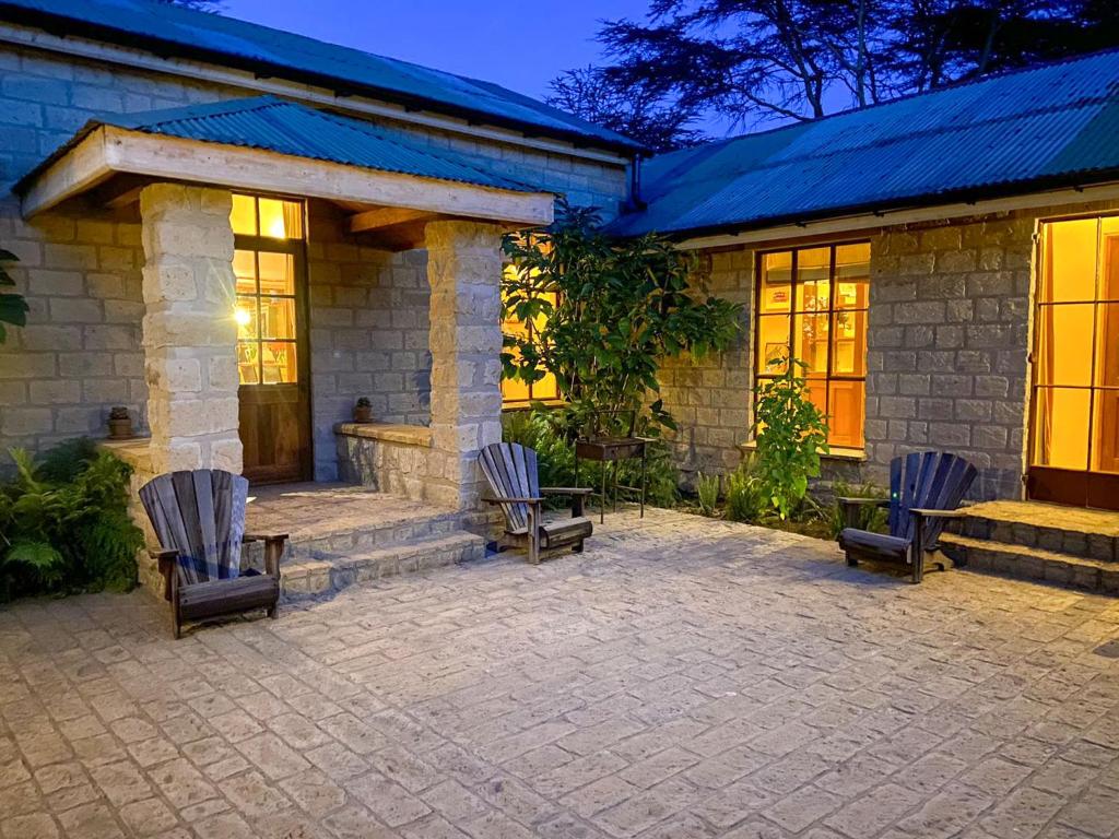 a house with three chairs sitting outside of it at Yellow House 3-bedroom Villa In Wildlife in Naivasha