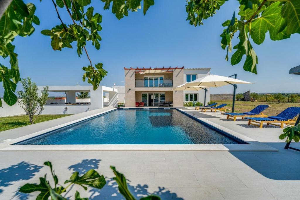 une piscine devant une maison dans l'établissement Villa Kotari in Zemunik Gornji - Haus für 10-12 Personen, à Simurina