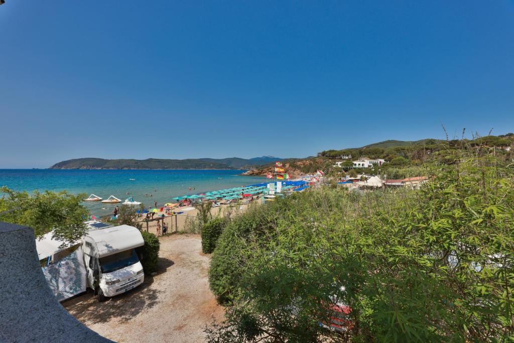 a van parked next to a beach with the ocean at Camping Bungalow Lido in Capoliveri