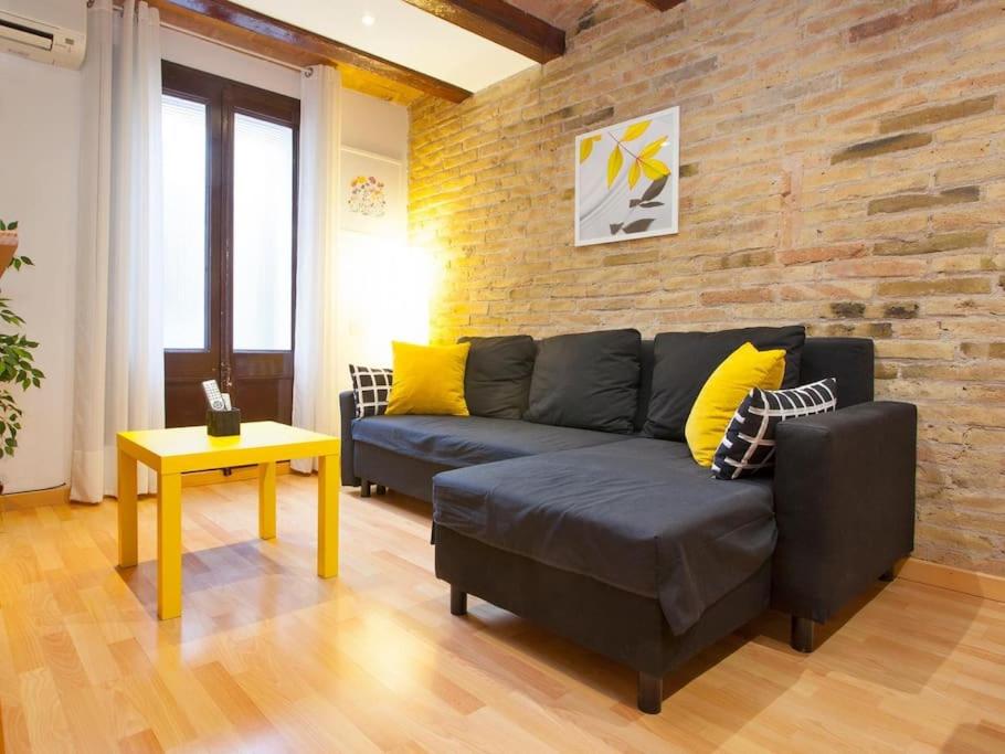 een woonkamer met een bank en een bakstenen muur bij Parallel - Family Flat 2 rooms in Barcelona