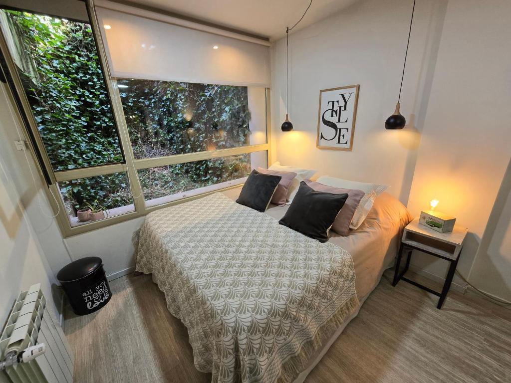 圣卡洛斯-德巴里洛切STUDIO EN EL CENTRO, 3 cuadras del centro cívico的一间卧室，里面有一张床和一扇大窗户。